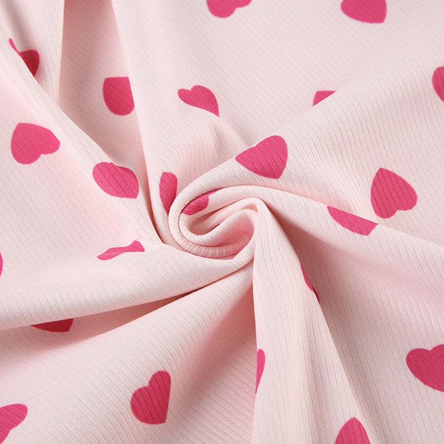 Close-up of the lettuce-edge hem and rib-knit texture of the Costume Inspire heart print pajama top, focusing on the soft pink fabric and red hearts.