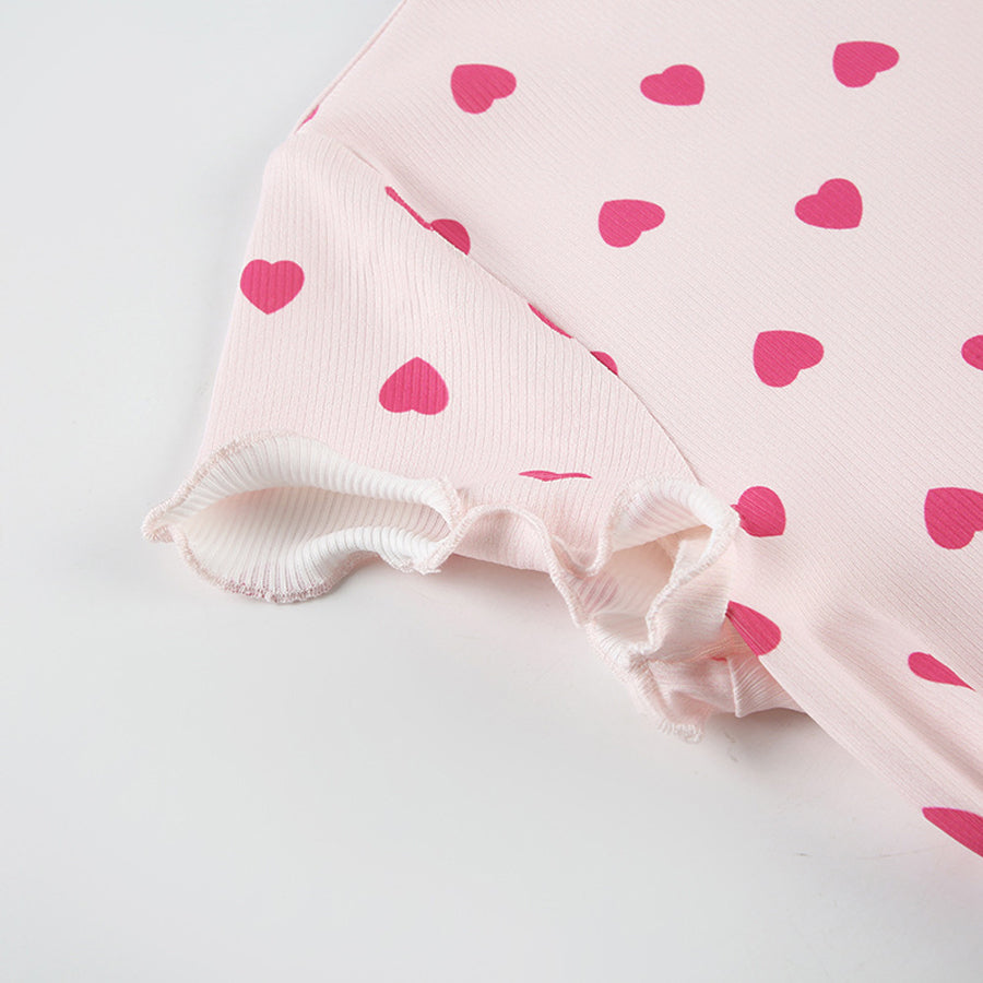 Close-up of the lettuce-edge hem and rib-knit texture of the Costume Inspire heart print pajama top, focusing on the soft pink fabric and red hearts.